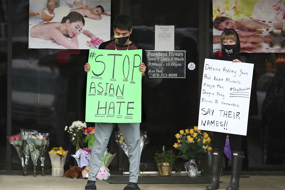 After dropping off flowers Jesus Estrella (L) and Shelby S. (R) stand in support of the Asian and Hispanic community outside Youngs Asian Massage parlor where four people were killed, Wednesday, March 17, 2021, in Acworth, Ga.