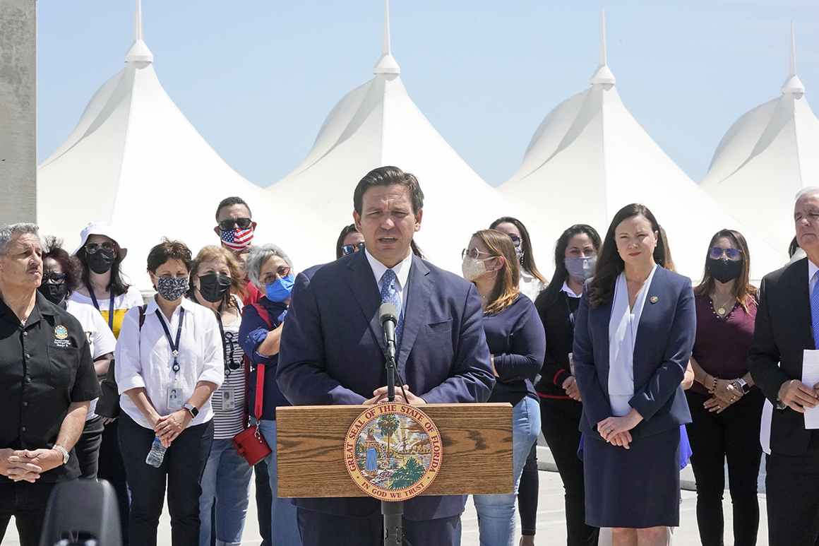 Florida Gov. Ron DeSantis speaks during a news conference surrounded by officials and cruise workers.