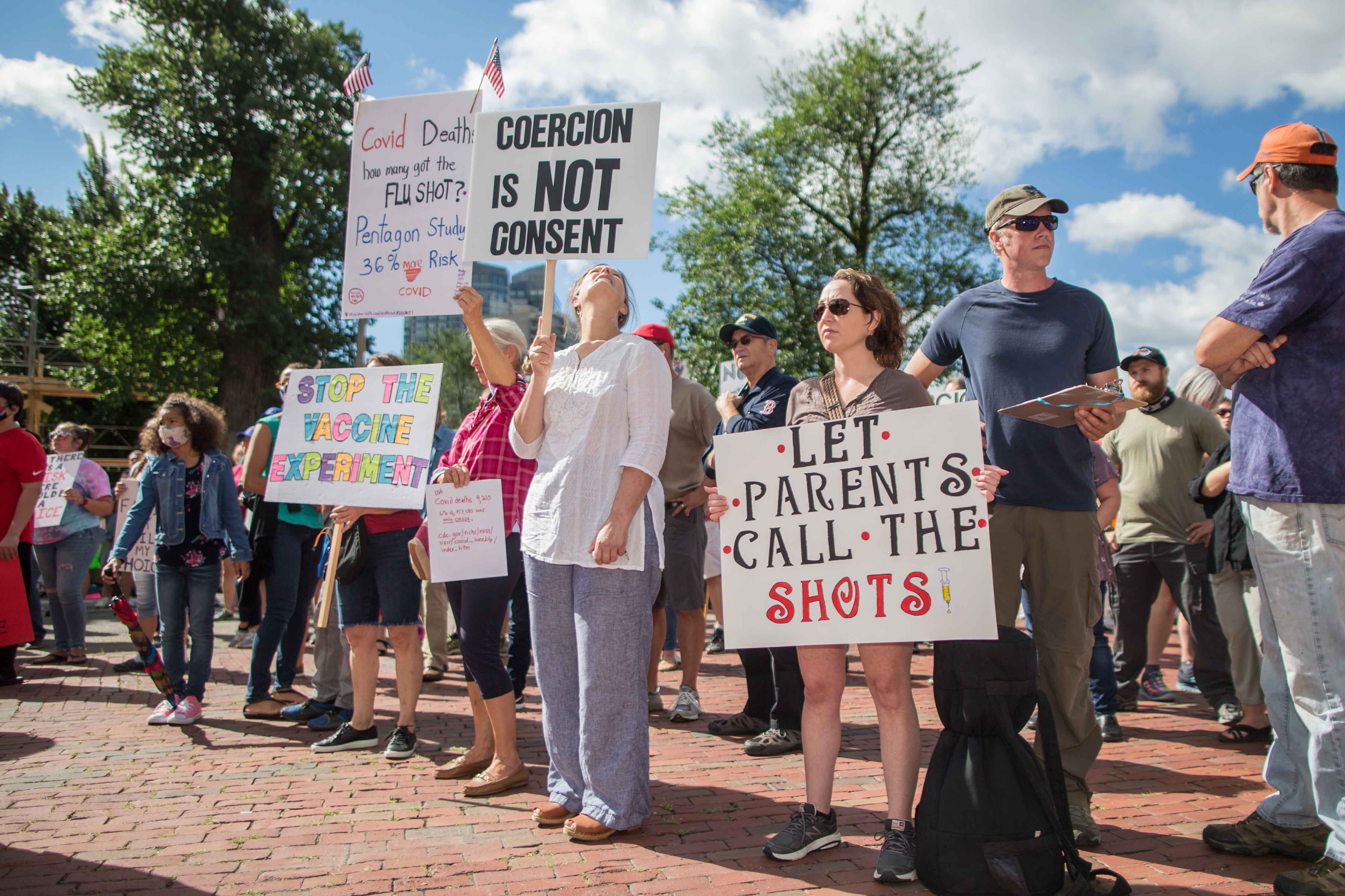 Anti-vaccine activists protest and hold signs in front of the Massachusetts State House in Boston, Massachusetts. 