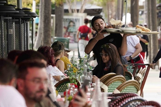 A waiter delivers food to patrons at a restaurant in Miami Beach, Fla.