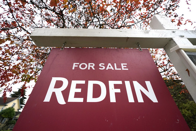 A Redfin For Sale sign stands in front of a house. 