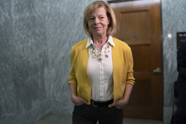 Sen. Tammy Baldwin, D-Wis., stands with hands in pockets in a marbled room at the Capitol.
