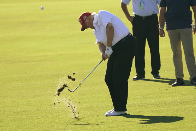 Former President Donald Trump hits a golf ball, taking out some grass from the ground.