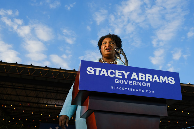 Georgia gubernatorial Democratic candidate Stacey Abrams speaks into a microphone behind a podium with her campaign insignia emblazoned in front.