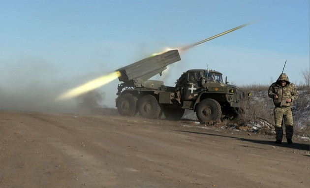 S member of Ukraine's military looks away as a BM-21Grad MLRS 122mm rocket launcher fires. 