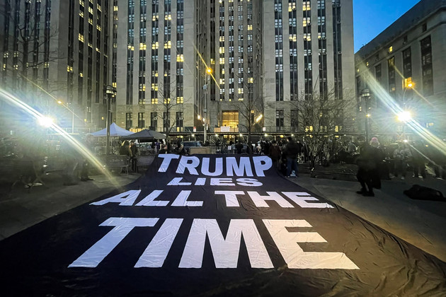 A large flag held by protesters that reads: TRUMP LIES ALL THE TIME.