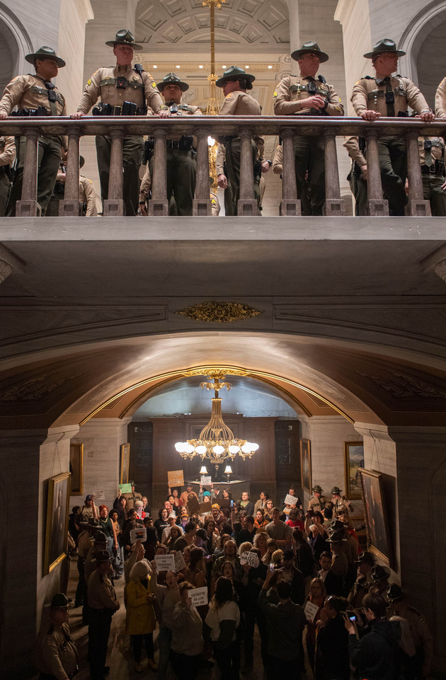 People protesting in the Tennessee state Capitol Building, with State Troopers standing on floor above them.