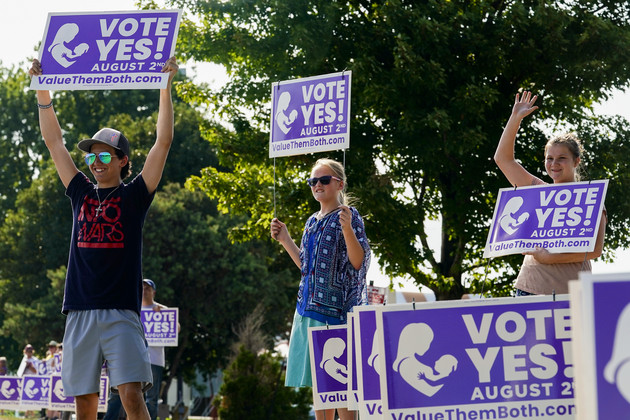 Young supporters of the Vote Yes to a Constitutional Amendment on Abortion hold up signs on Aug. 1, 2022, in Olathe, Kan. 