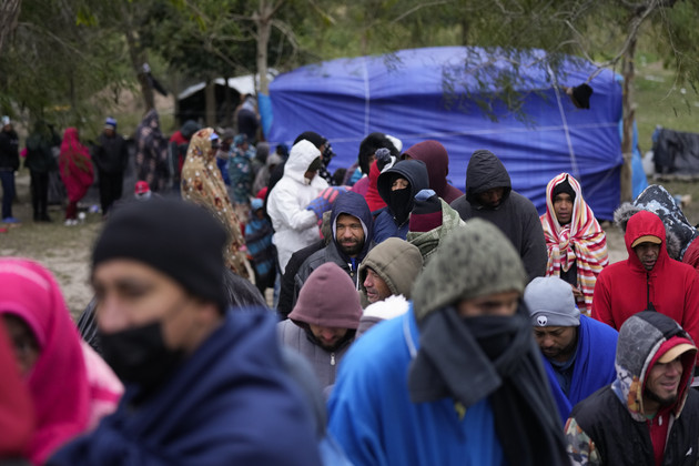 Migrants from Venezuela line up in the cold weather for hot drinks and food from volunteers.