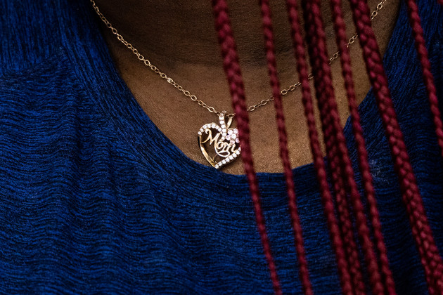 A close up of Shakina Gates’ necklace, showing the word mom with a heart around it.