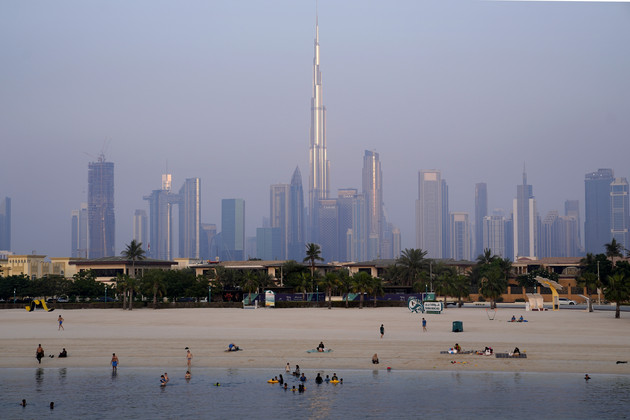 With the city skyline and Burj Khalifa, world's tallest building in background, people enjoy swimming in Dubai, United Arab Emirates.