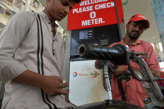 An employee fills petrol in a motorcycle at a fuel station