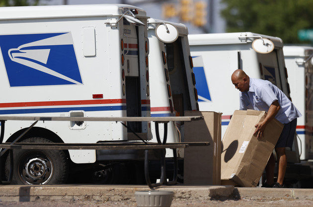 A mail carrier loads a van.